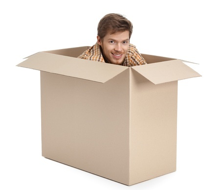 Young man peeking out of a cardboard box